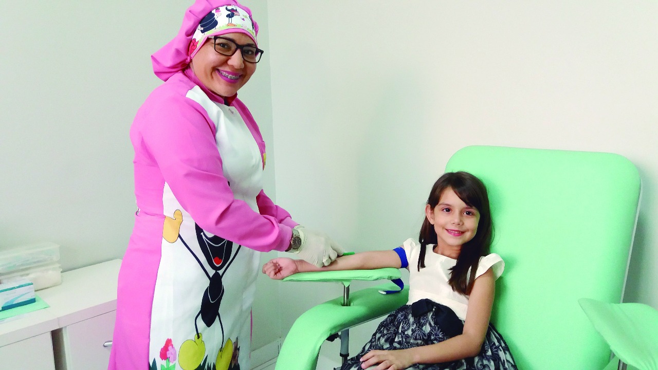 Enfermeira com jaleco colorido atendendo a uma criança sorridente